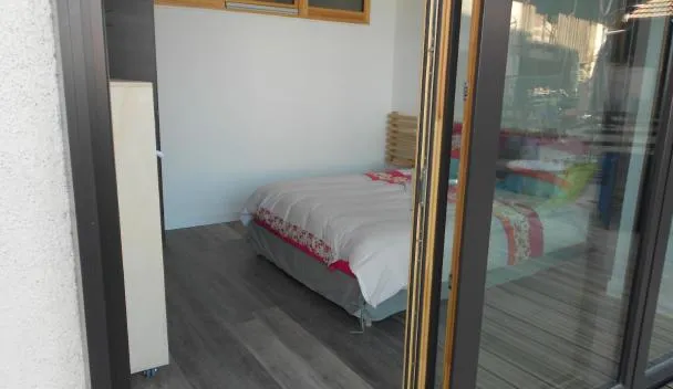 Bedroom with single bed, floral bedding, wooden slatted headboard and sliding glass door opening to a colorful playroom at Gîte De La Ferme in Gundolsheim