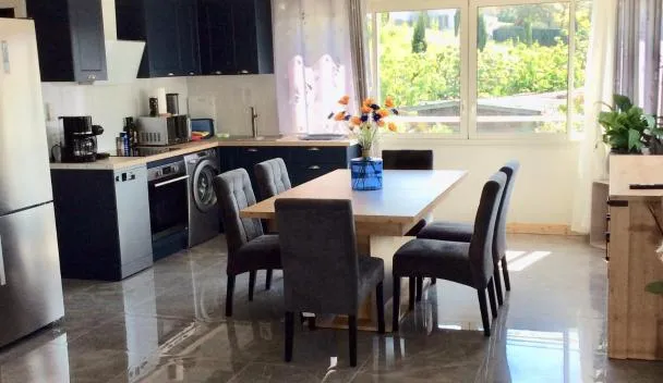 Open-plan kitchen and dining area with black cabinets, stainless fridge, coffee maker, front-load washer and garden view at bienvenue chez Alain et Marie in Antibes