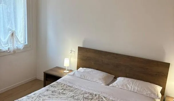 Double bed with floral duvet, wooden headboard, bedside tables with lamps, folded towels and exposed wooden ceiling beams at Laguna Prive' - with private parking in Venice