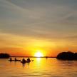 a group of people in canoes on a lake at sunset