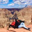 two people sitting on a rock at the grand canyon