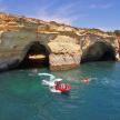 a group of people in a boat in the water near a cave
