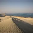 a view of a desert with the ocean in the background