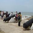a group of people standing near the ocean with cannonballs