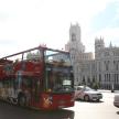 a red double decker bus driving in front of a building