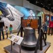 a group of children looking at a liberty bell in a museum