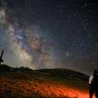 a man standing in a field looking at the milky way