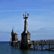 a statue in the middle of the water next to a pier