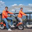 two men in orange jackets are riding motorcycles