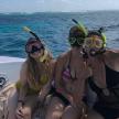 three women in bathing suits sitting on a boat in the ocean
