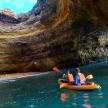 two people in a kayak in the water near a cave