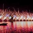 a group of people in a boat in the water with fireworks