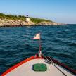 a boat with a flag on the water with a lighthouse