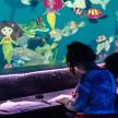 two children sitting at a table in front of a aquarium