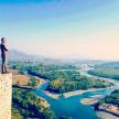 a man standing on the edge of a cliff overlooking a river