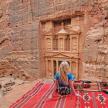 a little girl sitting on a rug in front of a building