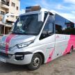 a pink and white bus parked on a street