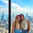 two women posing for a picture at the top of a skyscraper