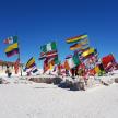 a group of flags on a sandy beach with people