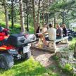 a group of people sitting at a picnic table with a atv