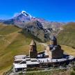 an old church on a hill with mountains in the background