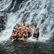 a group of people posing in front of a waterfall
