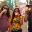 three women drinking cups of coffee on a street