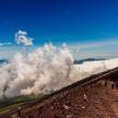 a group of people standing on top of a hill with clouds