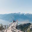 two people standing on a viewing platform on a mountain