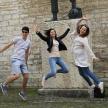 a group of three people jumping in front of a statue