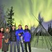 a group of people standing in the snow under the northern lights