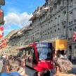 a red bus on a city street with people