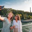 two women taking a picture of the eiffel tower