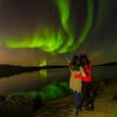 two people are looking up at the northern lights
