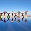 a group of people standing on the beach with their hands in the water