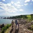 two people walking on the rocks near the water