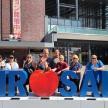 a group of people standing behind a sign with a red heart