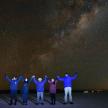 a group of people holding their hands up in the night sky