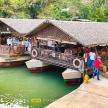 people standing on a dock with two boats on the water