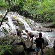 three people standing on rocks near a waterfall
