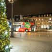 a double decker bus parked next to a christmas tree