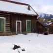 an old log cabin with snow on the ground
