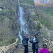 two people standing on stairs in front of a waterfall