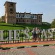 two people standing in front of a sign in front of a castle