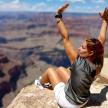 a woman laying on the edge of the grand canyon