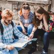 three people sitting on steps looking at a map