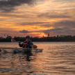 a man in a canoe on the water at sunset