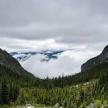 a view of a mountain valley with trees and clouds