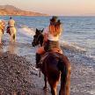a group of people riding horses on the beach