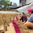 two young girls are sitting next to a bunch of grass